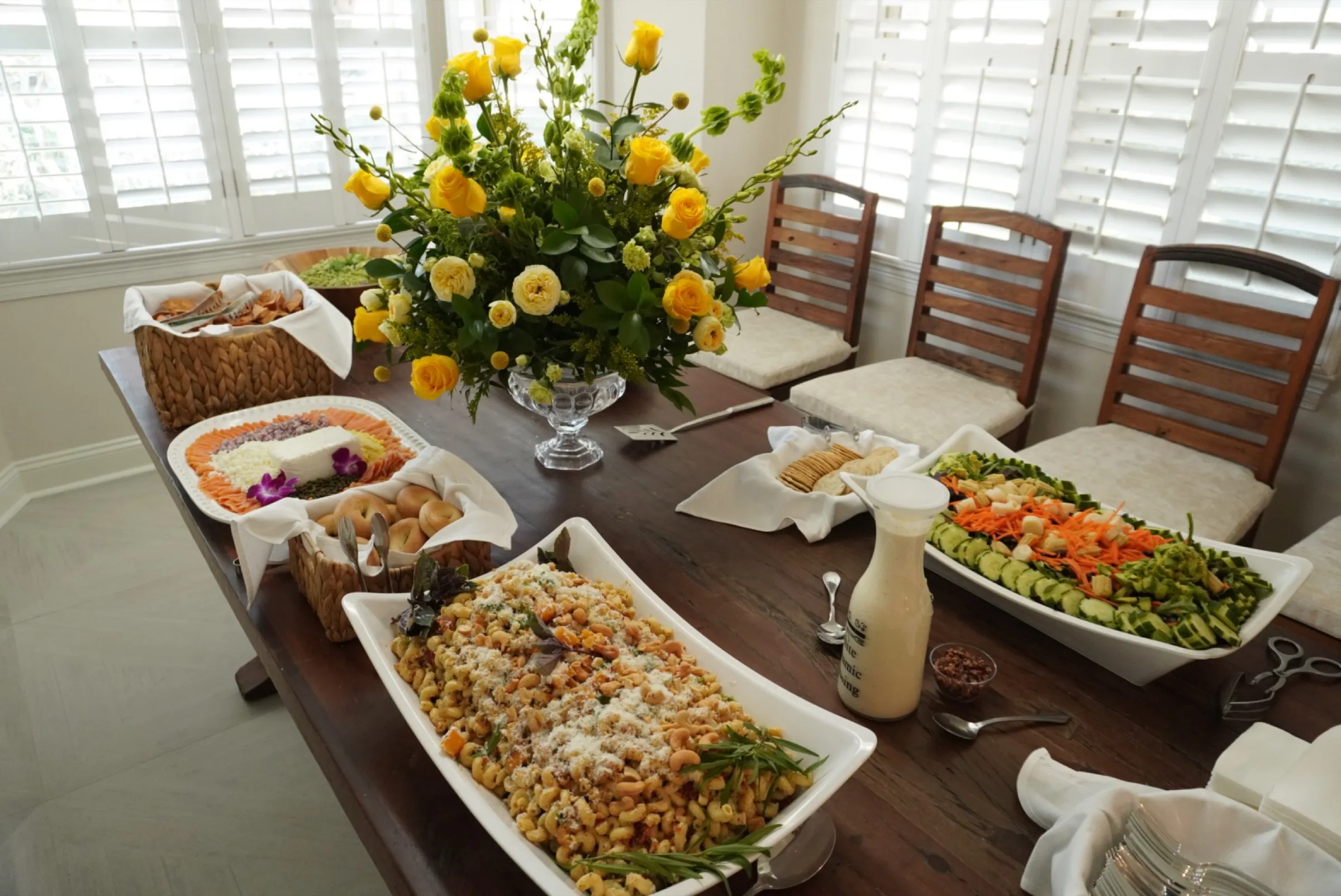 Elegant home dining table spread with yellow flowers and catered dishes
